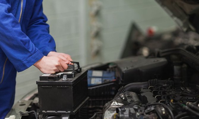 Il sort la batterie de la voiture.